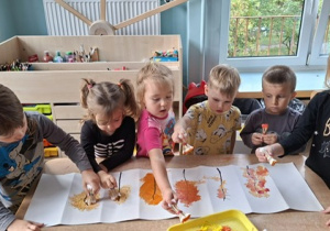Dzieci z grupy 3 malują patyczkami liście na drzewie, na kartonie- praca plastyczna