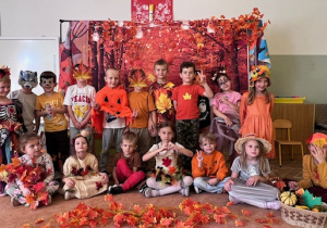 Grupowe zdjęcie dzieci z grupy 5 na tle obrazu z jesiennymi liśćmi