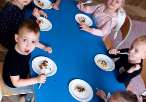 Dzieci z grupy pierwszej jedzą sałatkę owocową samodzielnie przygotowaną .