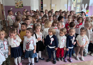 Dzieci stpjące na dywanie podczas śpiewania hymnu Polski.