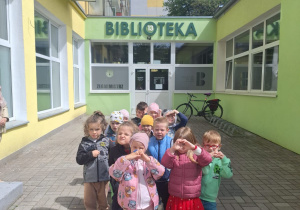 Dzieci z grupy 2 stoją razem przed wejściem do biblioteki