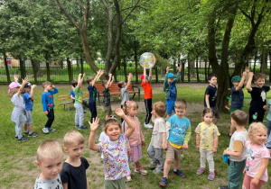 Dzieci tańczą i bawią się dmuchaną piłką w ogrodzie przedszkolnym