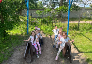 Dzieci bujają się na drewnianych huśtwakach w kształcie koni