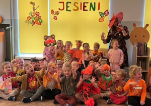 Zdjęcie grupowe na tle napisu bal jesieni dzieci z grupy 3 razem z panią muzyczką