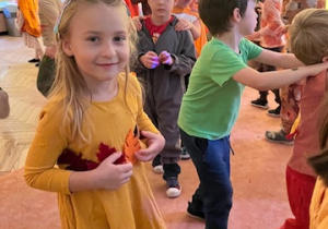 Tańczące dzieci i uśmiechnięa dziewczynka z grupy 3 w jesiennej sukience