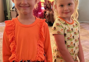 Dwie dziewczynki z grupy 3 pozują uśmiechnięte. Jedna w przebraniu dyni, druga w jesiennej sukience