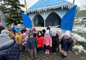 Dzieci z grupy 2 spacerują po bajkowej ścieżce, tu stoją przed domem Królowej Śniegu