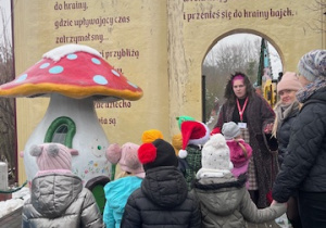 Dzieci przechodzą przez magiczne wrota do krainy bajek, podczas spaceru po ścieżce bajek