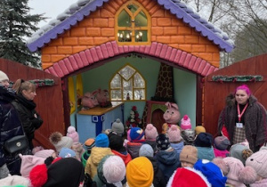 Dzieci słuchają opowiadania przewodnika o bajce 3 świnki