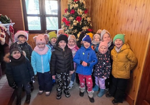 Dzieci z grupy 3 z wizytą w domu Dziada Mroza, stoją a w tle znajduje się choinka