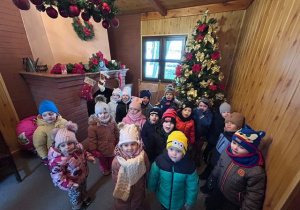 Dzieci z grupy 2 z wizytą w domu Dziada Mroza, stoją a w tle znajduje się choinka