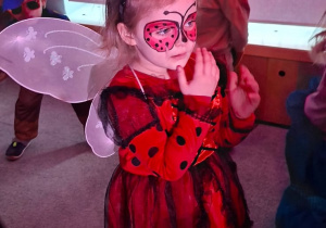 Dziewczynka z grupy 2 stoi w sali podczas balu, przebrana jest za biedronkę