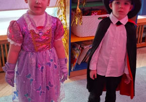 Dwójka dzieci z grupy 2 stoi podczas balu, księżniczka i czarodziej w kapeluszu