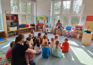 Dzieci z grupy 3 siedzą na dywnie i rozmawijają z panem Markiem