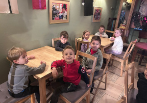Dzieci z grupy 2 siedzą przy stolikach w Baśniowej Kawiarence