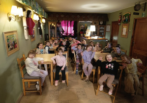 Grupowe zdjęcie dzieci z grupy 5, siedzących przy stolikach