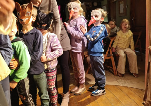 Przedszkolaki biorą udział w przedstawieniu, na twarzach mają maski różnych zwierząt, ustawieni sa w pociąg