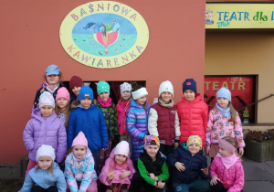 Grupowe zdjęcie dzieci z grupy 4 przed wejściem do Baśniowej Kawiarenki