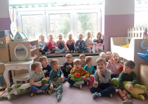 Wszystkie dzieci z grupy 1 siedzą na dywanie ze swoimi dinozaurami