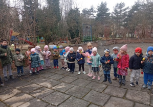 Dzieci z grupy 1 stoją na tarasie i grają na instrumentach