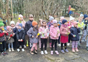 Dzieci z 2 gr grają na instrumentach, stojąc na tarasie