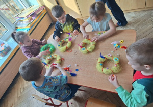 Dzieci z grupy 3 przyczepiają ozdoby do swoich wianków