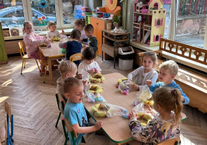 Dzieci z gr 2 siedzą przy stolikach i dekorują swoje wianki wielkanocne