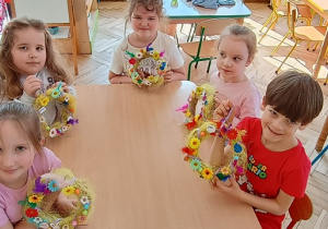 Dziewczynki i chłopiec z gr 4 prezentują ozdobione przez siebie wianki