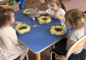 Dziewczynki z gr 1 ozdabiają żółte wianki