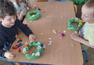 chłopcy i dziewczynka z gr 3 ozdabiają wianki