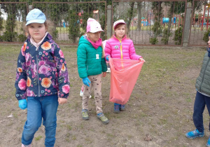 Dziewczynki z gr 4 z workiem na śmieci w rękach zbierają śmieci