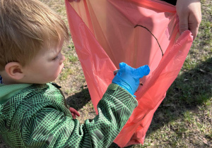 Chłopiec z gr 1 wrzuca do worka śmieć znaleziony w ogrodzie przedszkolnym