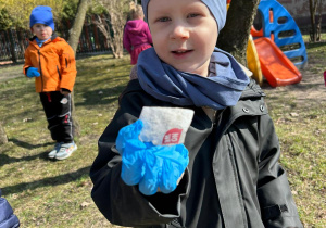 Przedszkolak z gr 2 pokazuje znalezioną kartę papieru