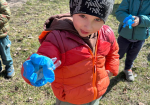 Chłopiec z gr 1 trzyma w rączce w rękawiczce znalezione śmieci