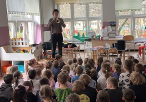 Dzieci oglądają i słuchają jak pan gra na trąbce