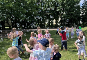 Tańce dzieci w ogrodzie pośród baniek mydlanych