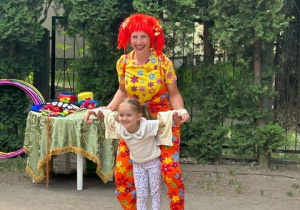 Dziewczynka z 2 grupy stoi na rownoważni z panią z cyrku