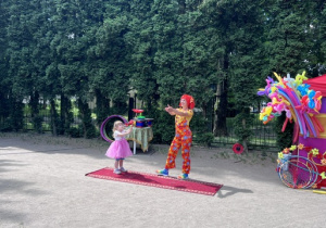 Dziewczynka z 1 grupy stoi na scenie i trzyma kijek, na którym wiruje dysk