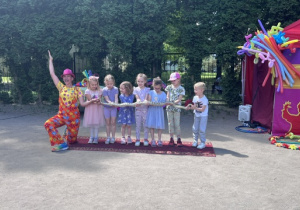 Dziewczynki i chłopcy stoją w rzędzie i trzymają węża