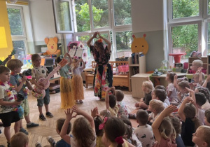 Dzieci na scenie tańczą podnosząc ręce do góry z panią Nutką