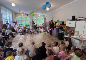 Dzieci z całego przedszkola siedzą na dywanie i słuchają przywitania wygłaszanego przez panią dyrektor