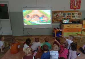 Dzieci oglądają film na tablicy multimedialnej o krainie kumpelkowo