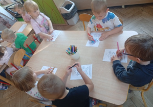 Dzieci przy stoliku kolorują postać z projektu